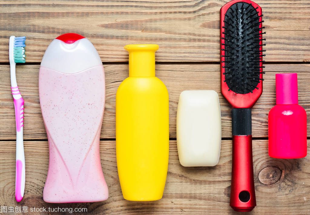 洗发香波, 沐浴露, 肥皂, 香水, 牙刷, 梳子。产品为美容卫生保健服务。木桌上的顶部视图